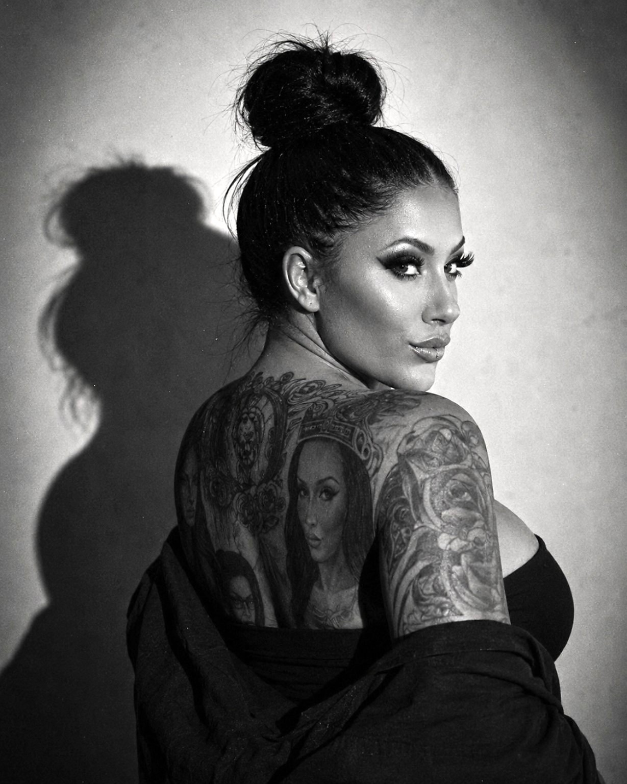 Jasmin Jenny blickt über ihre Schulter; Schwarzweißporträt mit Rückentattoos und markantem Schatten